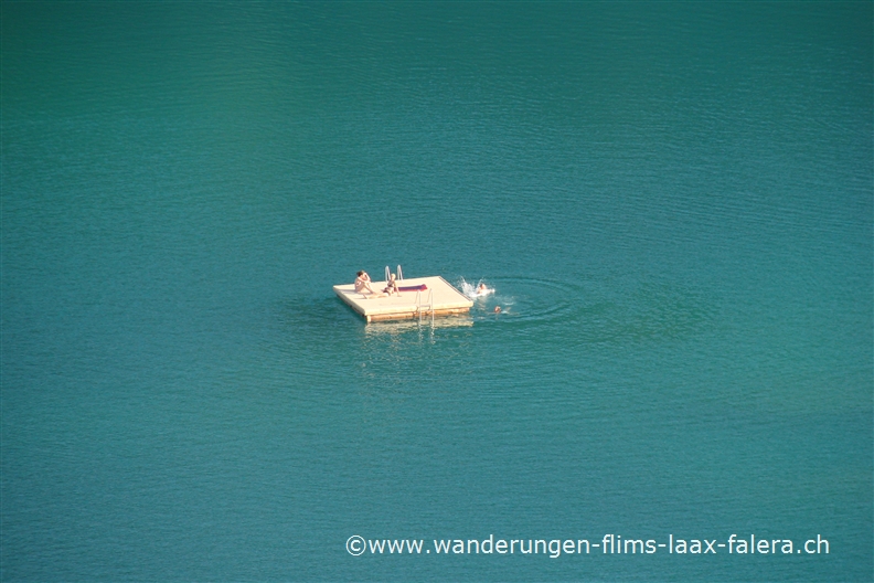 Ein Floss mit einigen Badegästen treibt auf dem Caumasee