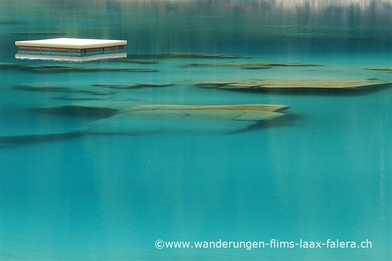 Das Floss auf dem Caumasee treibt über schöne durch das Wasser schimmernde Gesteinsformationen